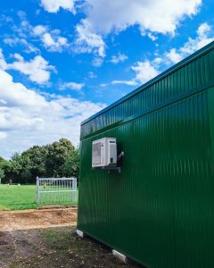 Grüne Außenfassade der Schulerweiterung mit Blick auf den Fußballplatz
