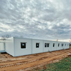 Aufnahme eines hellen Containergebäudes, das als Sozialunterkunft dient, von außen