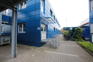 Blaues Containergebäude, das als Büro oder zur Verwaltung dient, fotografiert von außen