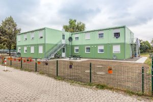 Aufnahme von einem grünen Containergebäude, das als Wohnunterkunft dient, von außen