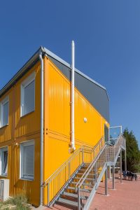 Aufnahme von einem gelben Containergebäude, das als Wohnunterkunft dient, von außen