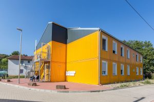 Aufnahme von einem gelben Containergebäude, das als Wohnunterkunft dient, von außen