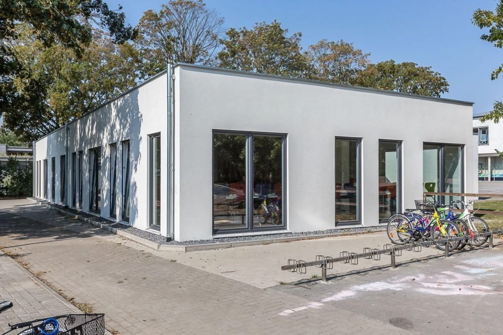Helles Containergebäude einer Schule von außen fotografiert