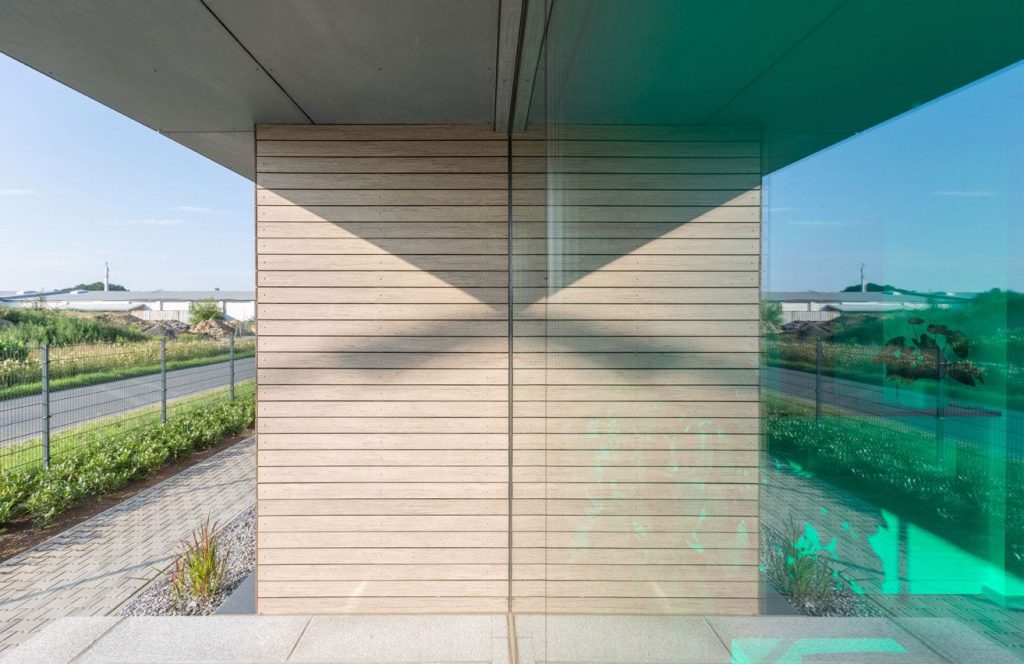 Künstlerisches Foto eines Bürocontainers. Fotografiert von der Seite wird die Umgebung durch die Reflektion der Fensterscheibe erweitert