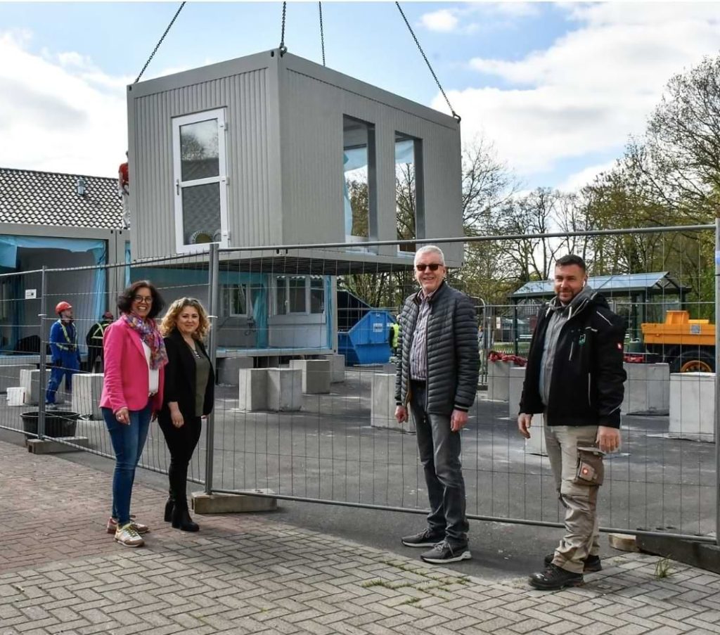 Schwebendes Klassenzimmer: Schulleiterin Christiane Westermann, Nachhaltigkeitsmanagerin Katharina Belz, Allgemeiner Vertreter des Bürgermeisters Heiner Themann und der 2. Bauleiter verfolgen den Aufbau der Anbau-Module. Foto: Vollmer | Quelle: om-online.de