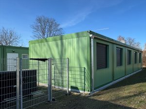 Grünes Containergebäude, das als Wohnanlage für Geflüchtete dient