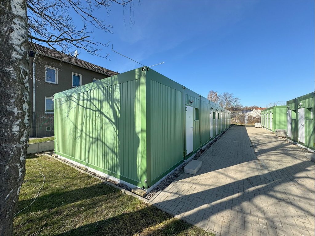 Grünes Containergebäude, das als Wohnanlage für Geflüchtete dient