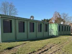 Grünes Containergebäude, das als Wohnanlage für Geflüchtete dient