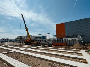 Aufnahme eines gelben Kranwagens vor einer im Bau befindlichen Modulbau-Unterkunft