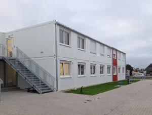Außenansicht einer Flüchtlingsunterkunft bestehend aus mehreren weißen Modulen mit farbigen Akzenten