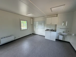 Innenansicht eines Containergebäudes, welches als Aufenthalts- und Materialraum genutzt wird, mit einer kleinen Küchen- und Nasszeile