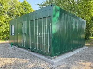 Außenansicht eines grünen Containergebäudes, welches als Aufenthalts- und Materialraum genutzt wird