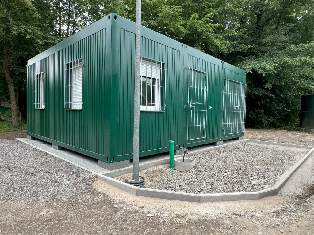 Außenansicht eines grünen Containergebäudes, welches als Aufenthalts- und Materialraum genutzt wird