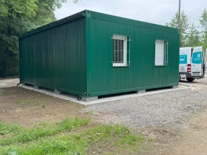Außenansicht eines grünen Containergebäudes, welches als Aufenthalts- und Materialraum genutzt wird