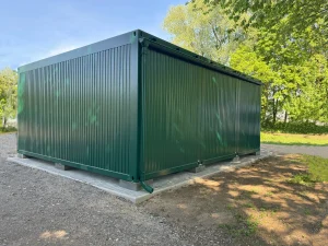 Außenansicht eines grünen Containergebäudes, welches als Aufenthalts- und Materialraum genutzt wird